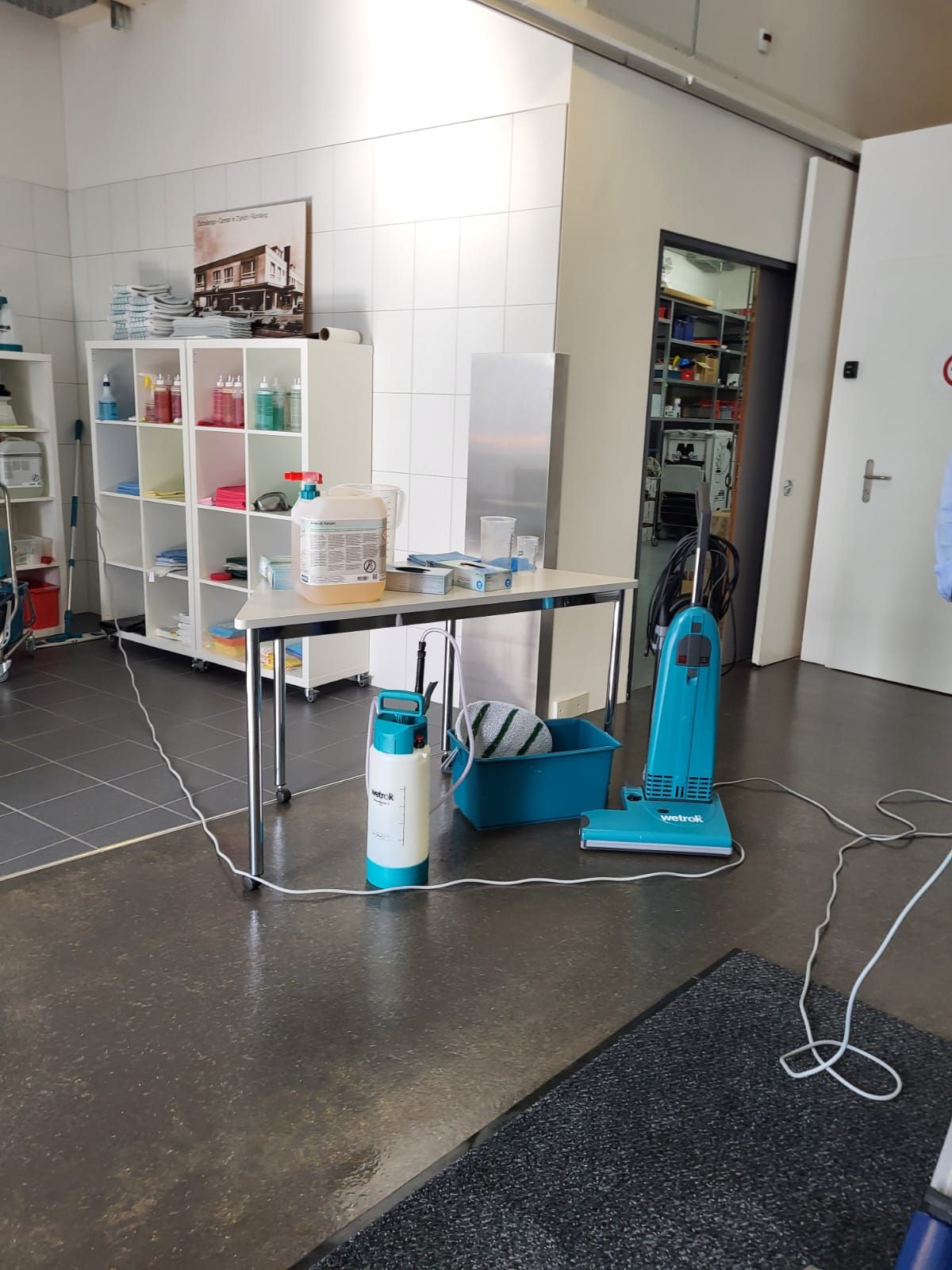 Reinigungsgeräte, Staubsauger und Sprühgerät, in einem aufgeräumten Raum