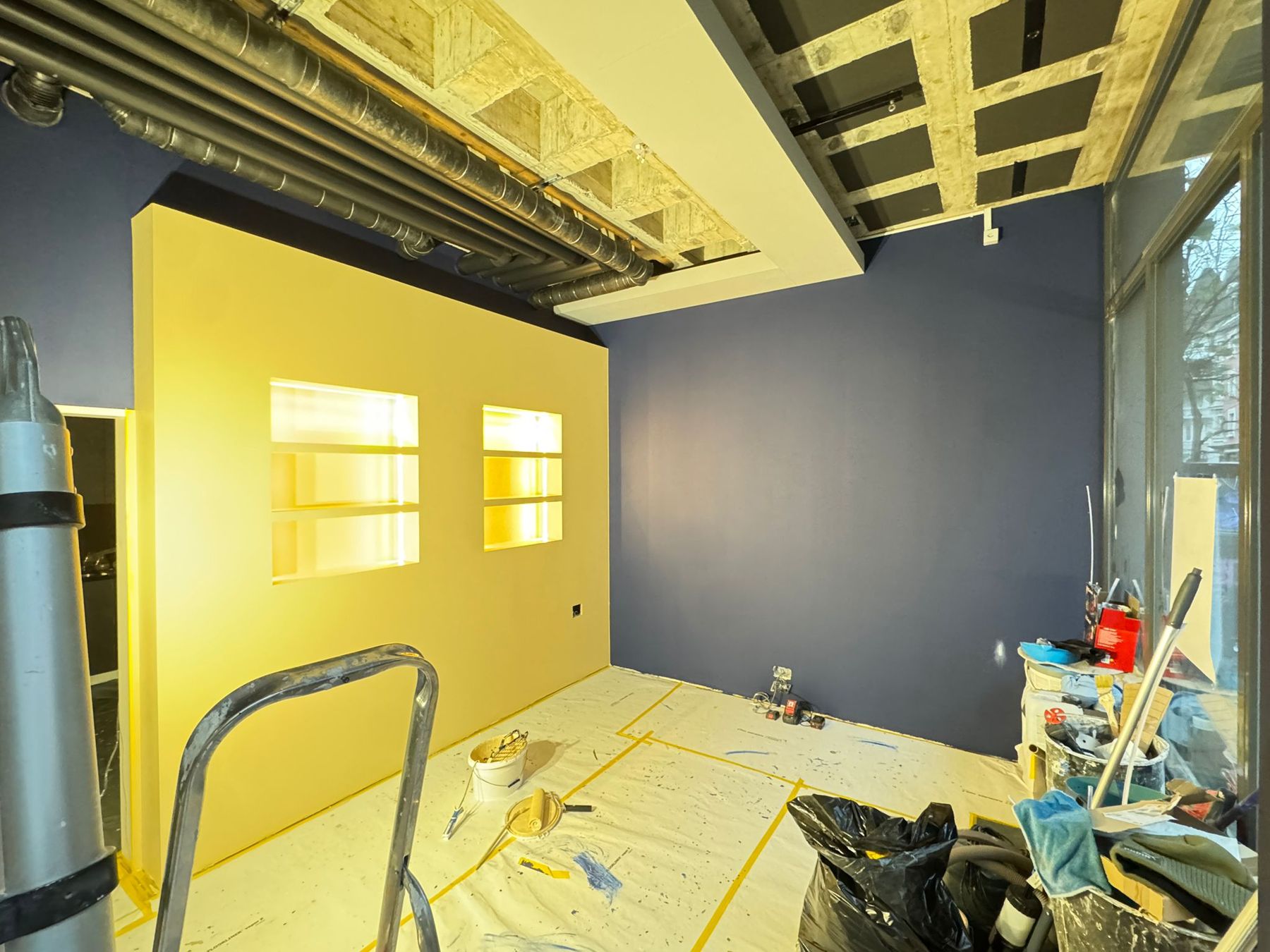 Renovation: frisch gestrichene gelbe und dunkelblaue Wände, Boden abgedeckt